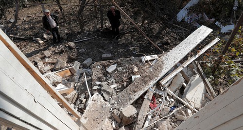 Men standing next to the ruins of a house destroyed by shelling in the city of Martuni, October 14, 2020. Photo: REUTERS / Stringer