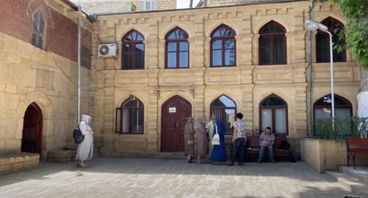 Tourists in a courtyard of a mosque in Derbent. Screenshot: https://www.youtube.com/watch?v=1rUg3LrF6kQ