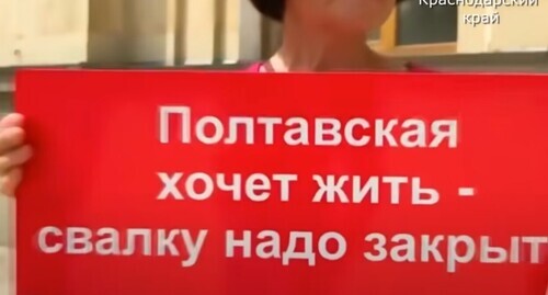 A protester against the garbage landfill located in the village of Poltavskaya holding a banner. Screenshot of the video https://www.youtube.com/watch?v=y7Emul88e0k